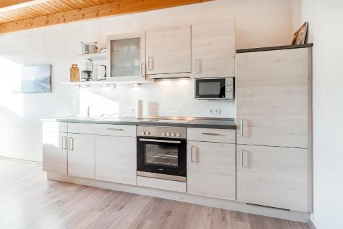 a kitchen with white cabinets and a stove at Ferienwohnung Seepferdchen für 3 Personen am Badesee Tannenhausen in Aurich