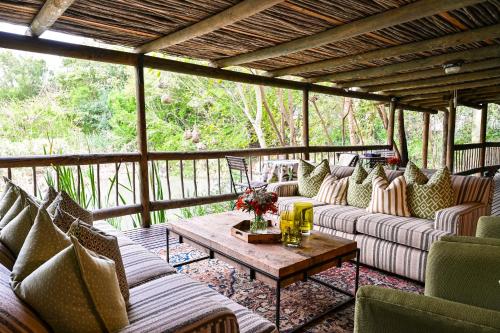 a screened in porch with couches and a coffee table at Woodall Country House and Spa in Addo