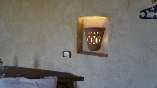 a light on the wall of a room with a table at Gazrashek Siwa Hot spring& trips Haven in Siwa