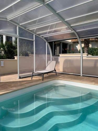 une terrasse avec une piscine et une chaise à côté d'un bâtiment dans l'établissement Piscine chauffée-Beauval et Châteaux-, à Cormeray