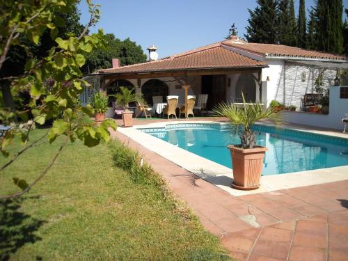 a swimming pool with potted plants next to a house at Finca La Ladera in Manilva