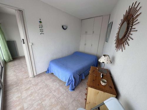 - une petite chambre avec un lit bleu et une table dans l'établissement Appartement cosy 4 pers avec parking à Port Camargue - FR-1-731-103, au Grau-du-Roi