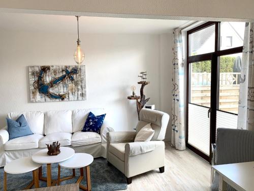 a living room with a white couch and two chairs at FeWo Seegras in Grödersby