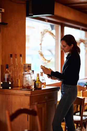 a woman standing at a bar with a bottle of wine at Au Vieux Champex in Champex