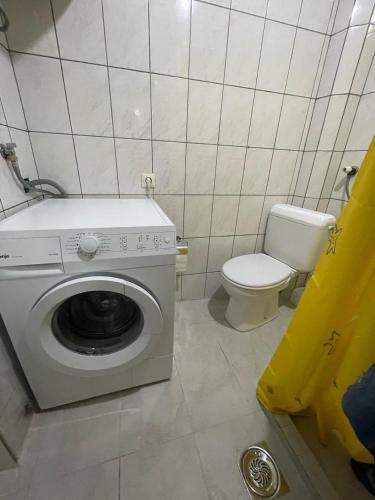 a bathroom with a washing machine and a toilet at Old City Home in Prizren