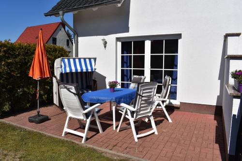 a patio with a table and chairs and an umbrella at Ferienhaus Schäferhund in Thiessow
