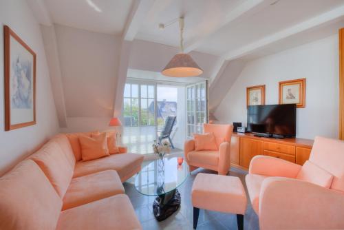 Il comprend un salon doté d'un mobilier orange et d'une télévision à écran plat. dans l'établissement Abaco 2N, à Wenningstedt