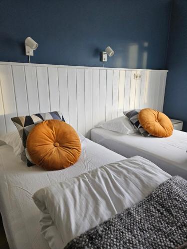 two beds with orange pillows on them in a room at Hótel Laugarhóll with natural hot spring in Laugarholl