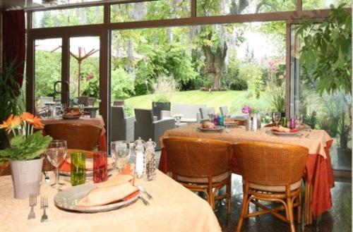 a dining room with tables and chairs with a view at Hôtel Beatus in Cambrai