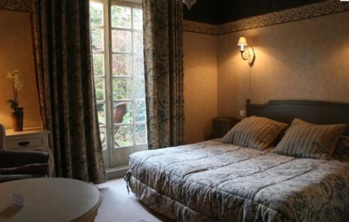 een slaapkamer met een bed en een groot raam bij Hôtel Beatus in Cambrai