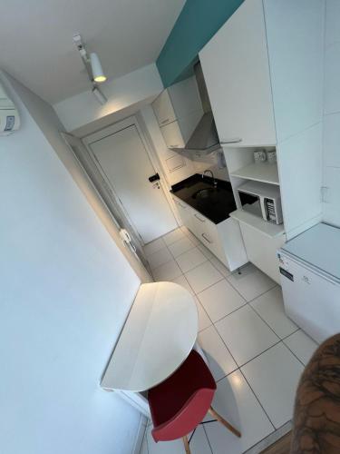 a small white kitchen with a stool and a table at Flat Wise Confort in São Paulo