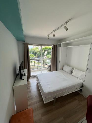a bedroom with a white bed and a balcony at Flat Wise Confort in São Paulo