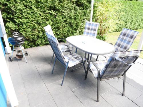 a table and chairs on a patio with a grill at "Blaues Haus am See mit Boot" in Warin