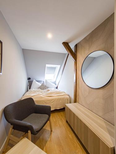 a small bedroom with a mirror and a chair at Radost Residence The Heart of Unique Living in Prague