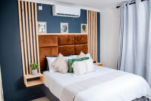 a bedroom with a white bed with a blue wall at Kanana Villas Maun 2 bedroom apartment in Maun