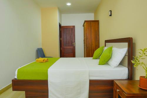 a bedroom with a bed with green and white pillows at Rosemary Villa - Welegoda, Matara in Matara