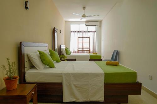 a bedroom with a large bed with green pillows at Rosemary Villa - Welegoda, Matara in Matara