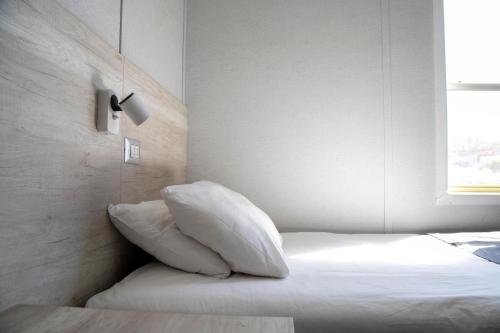 a bedroom with a bed with white pillows and a window at Hotel Village Chillepín in Choapa
