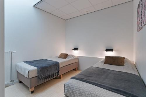 two beds in a room with white walls at Dock Hotel Stellendam in Stellendam