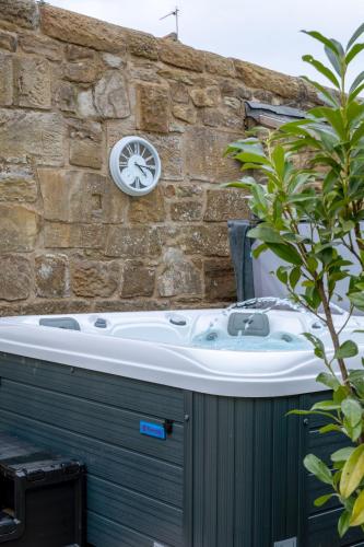 a hot tub sitting next to a stone wall at Rowan Cottage Lanchester-Escape Beyond Holiday Lets in Lanchester