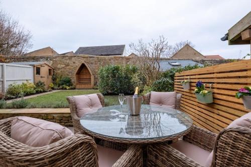 eine Terrasse mit einem Glastisch und Stühlen in der Unterkunft Rowan Cottage Lanchester-Escape Beyond Holiday Lets in Lanchester