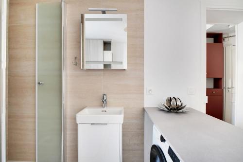 une salle de bain blanche avec un lavabo et un miroir dans l'établissement Jardin de Luxembourg - Arène de Lutece, à Paris