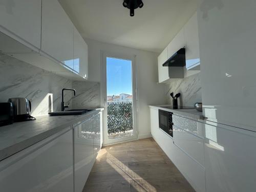 une cuisine avec comptoirs blancs et une grande fenêtre dans l'établissement Les Venitiennes, à Cannes