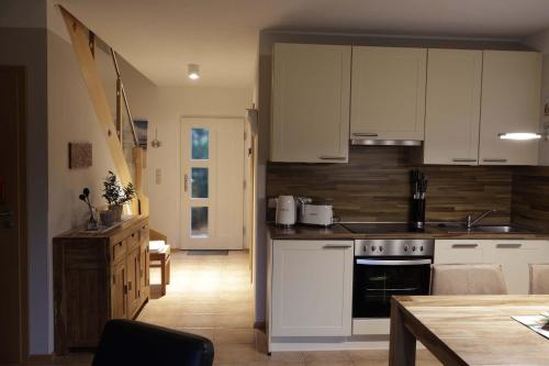 a kitchen with white cabinets and a stove top oven at Boddenblick 3B in Fuhlendorf