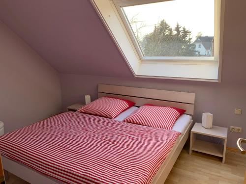 a bedroom with a bed with two red pillows and a window at Boddenblick 3B in Fuhlendorf