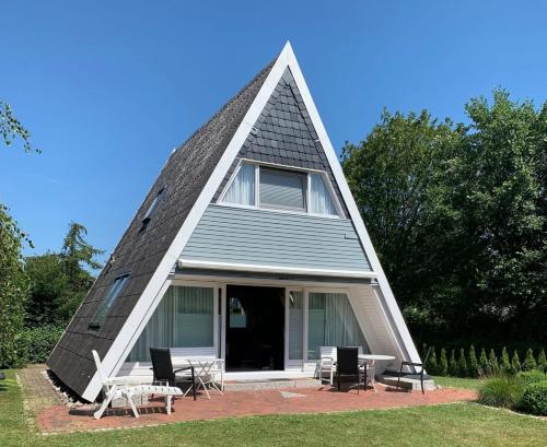 a house with a triangular roof with tables and chairs at Ferienhaus LiLeBe in Damp