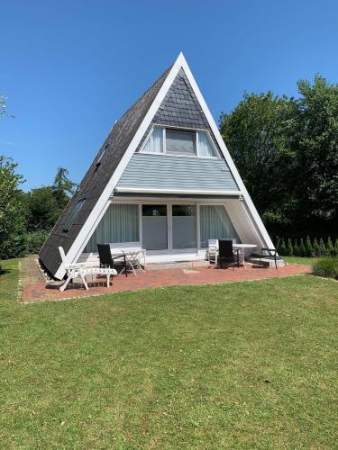 a house with a triangular roof with chairs and tables at Ferienhaus LiLeBe in Damp
