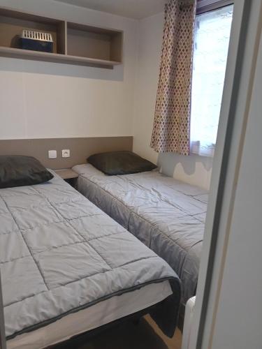 deux lits dans une chambre avec une fenêtre dans l'établissement MH 468 LUMINOSA 3ch dont 1 suite parentale et 2sdb proche des activités dans camping 4 étoiles, à Saint-Julien-en-Born
