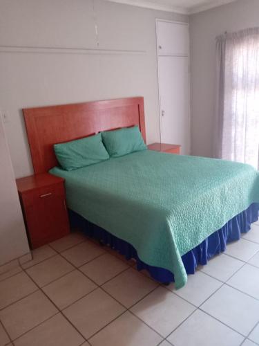 a bedroom with a bed with a green comforter at Simekhona Guest House in Aangewysd