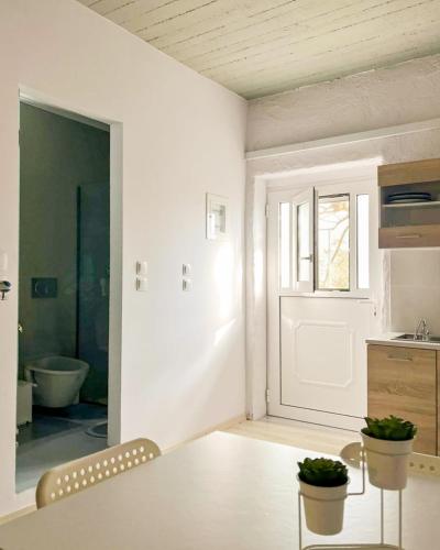 a white room with a table and a bathroom at Marina's Garden Nests - Holiday Bliss Getaways in Romanu