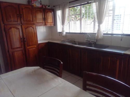 a kitchen with wooden cabinets and a sink and a table at Simekhona Guest House in Aangewysd