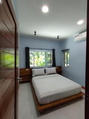 a bedroom with a bed and a window and a door at The Leaf Bankrut - Cosy Cottage in Ban Krut