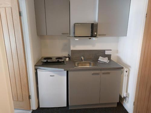 a small kitchen with a sink and a microwave at Anfieldstadiumroomz in Liverpool