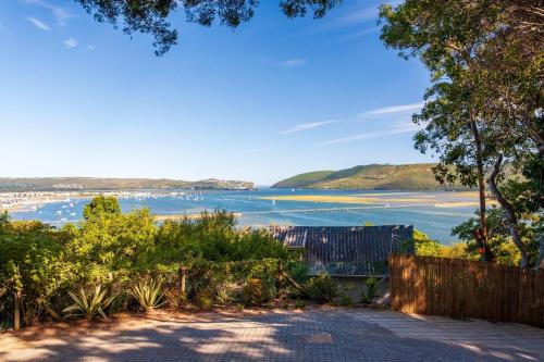 a view of a beach with a fence and trees at Loerie's Perch - On Knysna Lagoon in Knysna