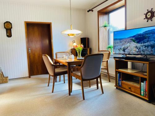 a dining room with a table with chairs and a television at Ferienhaus mit Charme DEL in Delmenhorst