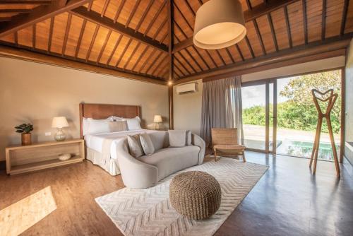 a bedroom with a bed and a couch and a chair at Colina Pousada SPA in Fernando de Noronha