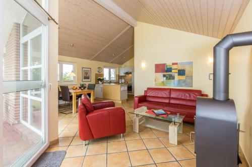 Una sala de estar con un sofá rojo y una mesa. en Haus im Apfelgarten 3, en Fehmarn