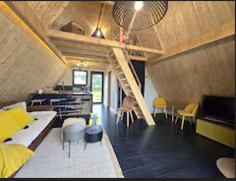 un salon avec un escalier dans une maison dans l'établissement le chalet d'hibs, à Montreuil-le-Chétif