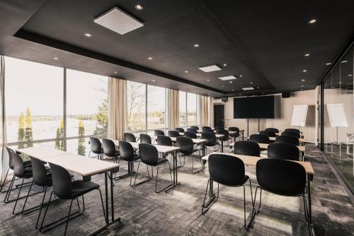 a conference room with tables and chairs and a screen at Scandic Gardermoen in Gardermoen