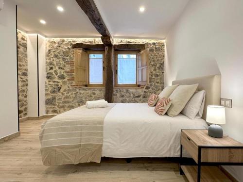 une chambre avec un grand lit et un mur en pierre dans l'établissement El Patio de Vespasiano-Calera- vistas a la iglesia junto al puerto, à Castro Urdiales