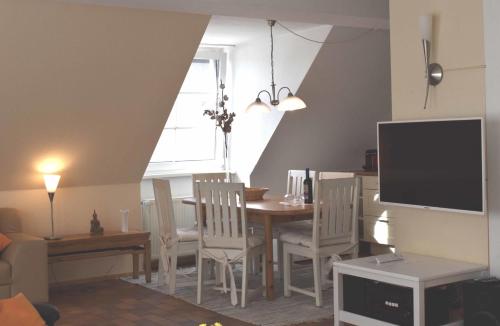 a dining room with a table and chairs and a television at Resi M5 in Prerow