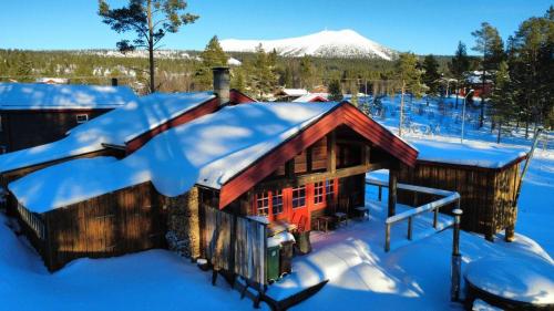 a log cabin in the snow with snow on the roof at Hot tub | Sauna | WiFi | Pets allowed in Lofsdalen