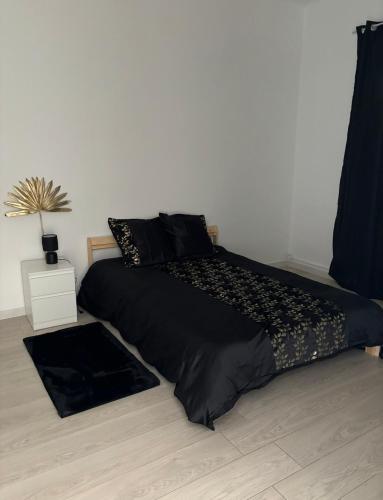 - un lit avec une couette noire dans une chambre dans l'établissement Appartement cosy Avignon, à Avignon