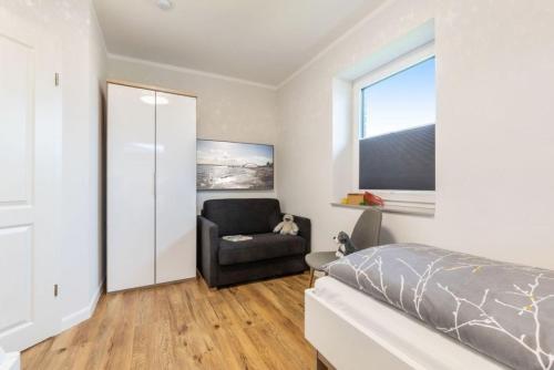 a bedroom with a bed and a chair and a window at Ferienhof Marquardt Bungalow 1 in Fehmarn