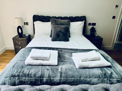 a large bed with two white towels on it at Knatchbull Cottage in Downhead