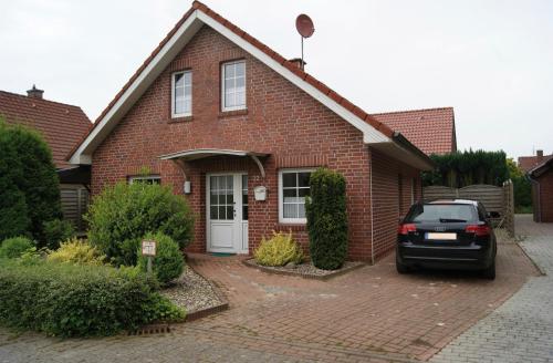 a red brick house with a car parked in the driveway at Ferienhaus Thesing in Sögel
